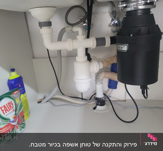 כיור עם צנרת וכלים מתחת לכיור במטבח